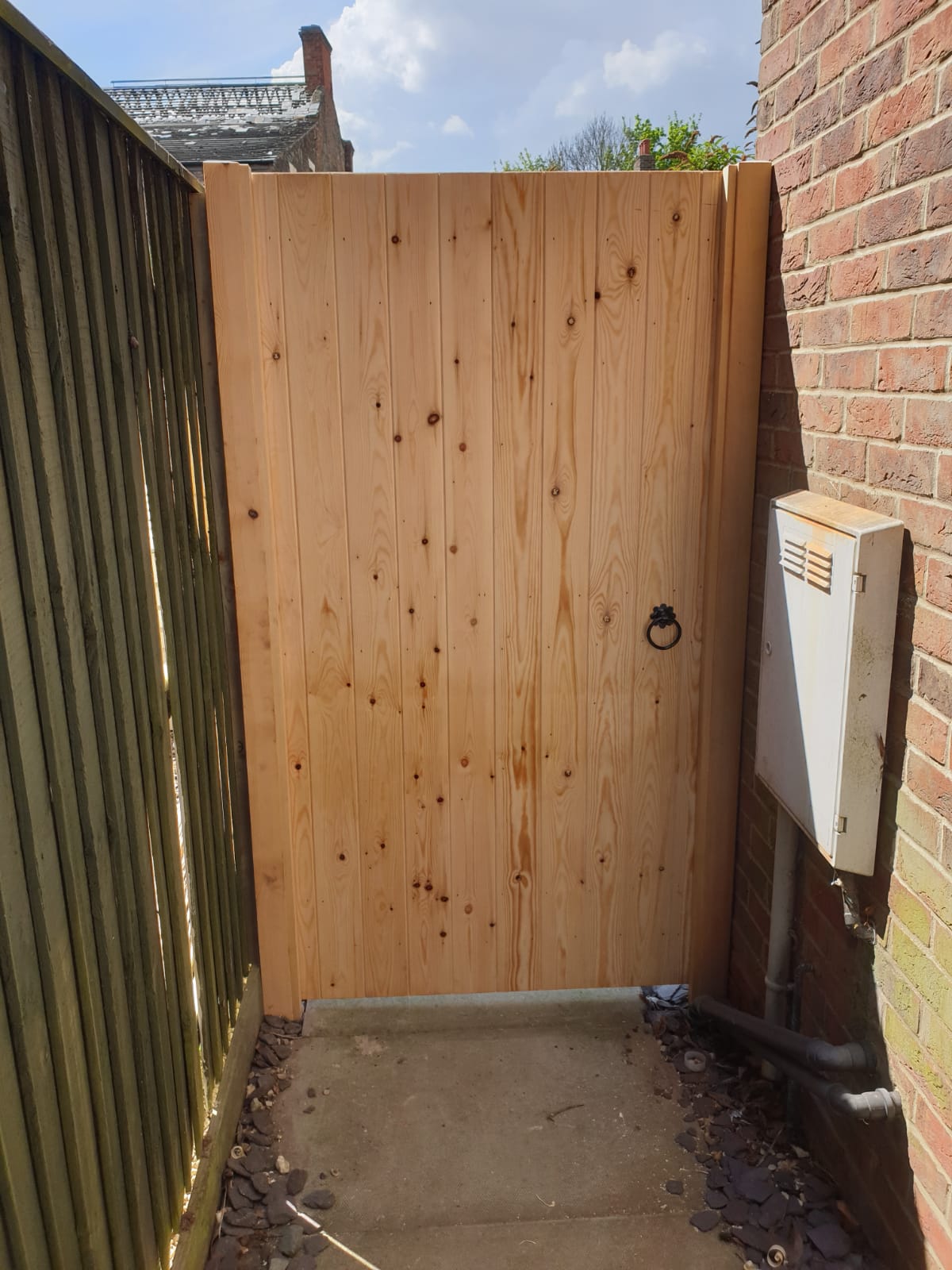 A new timber side gate between a fence and a brick wall