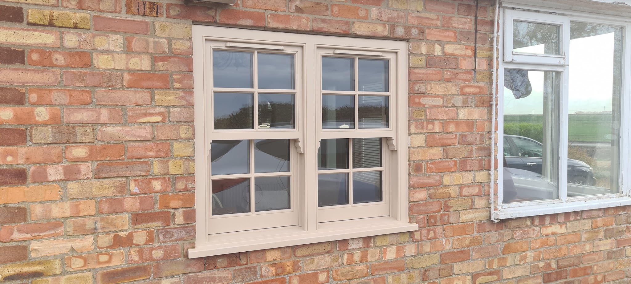 A newly fitted painted sash window in a brick wall